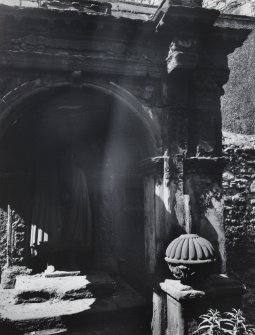 Detail of figure in recess of monument in wall of churchyard.