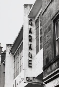 Detail of the lettering on the front of the garage: ' GARAGE' and 'OUT' seen from the South, with the garage in disrepair.