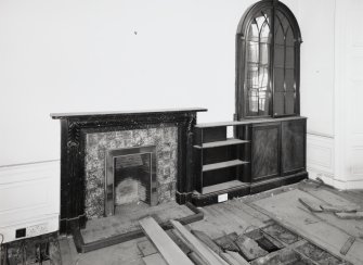 Interior, ground floor, North East room, view of fireplace and bookcase.