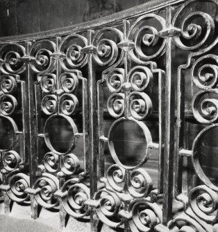 Interior-detail of wrought iron balustrade in front of curved bench in chapel.