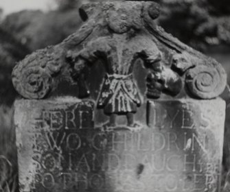 Detail of headstone showing female figure with skull and bone.