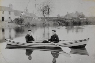 View of Waterside Cottages, with the River Tyne, and two men in a boat, in the foreground.