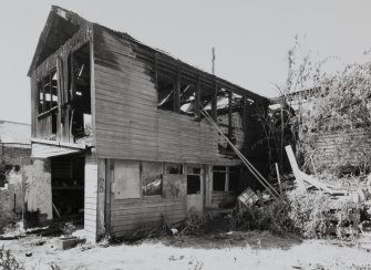 View of two storey wooden shed (to rear) from SE.