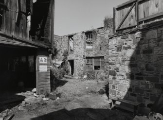 View of two storey wooden shed (to rear) and roofless building to E from SW.