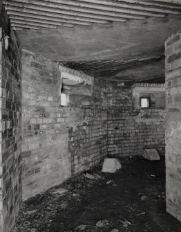 Interior view of type 27 pillbox, W segment showing two gun loops and fallen concrete angle blocks.  Also visible is part of the roof.