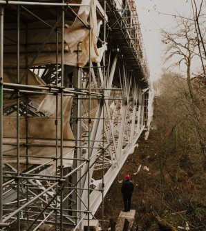 Oblique view from NNW of W side of bridge during re-furbishment, with human figure for scale.