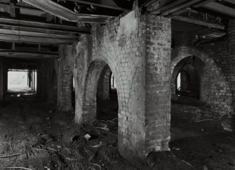 Newtongrange, Lady Victoria Colliery, Pithead Building (Tub Circuit, Tippler Section, Picking Tables)
Diagonal interior view from NE looking through arcades of brick arches separating the railway sidings passing under the colliery's surface buildings.  Wagons were filled from conveyors and hoppers in the floors above, which also housed the Picking Tables