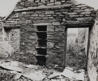 View of ruined interior of dwelling, showing shelved recess in kitchen.