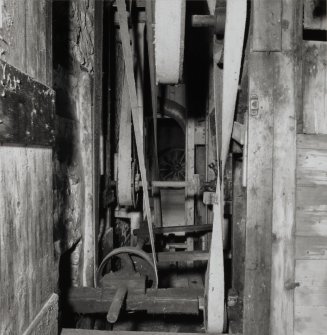 View of drive pulleys and belts for machine, side wall of building on left and the threshing machine on the right