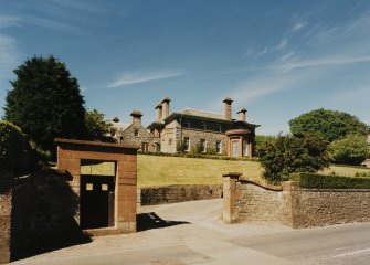 View from road to South showing entrance gates curving drive and principal facade