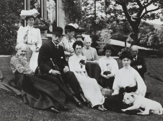 Copy of historic photograph showing group of people sitting in garden.