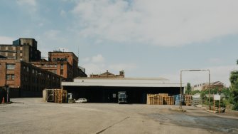 View from ESE of E end of N portion of factory, showing vehicle loading area (building no. 34, NS2796 7545), with Warehouse 1 behind (building no. 33, NS2794 7545), and the S portion of the factory visible to left