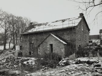 View of mill from W, showing gabled water wheel house towards SW end of NW elevation