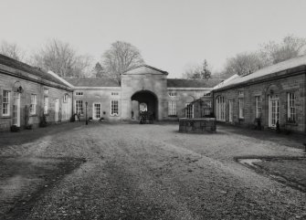 Interior view of courtyard from South West showing pedimented rear entrance, former stables and carriage houses and well