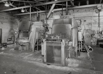 Motherwell, Craigneuk Street, Anderson Boyes
Heat Treatment (Dept. 12, west bay built 1945): Interior view from north east in west bay, showing two Ipsen sealed quench heat-treatment furnaces (TQ 7 left, and TQ 9 right).  Both are fired by pure endothermic gas from an adjacent gas producer.  Heat treatment is required for the hardening of components of machines, such as gears.  The furnaces are loaded from a rail-mounted conveyor (foreground).