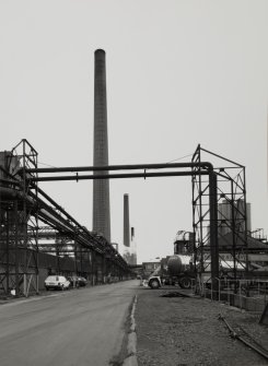 View from N along W side of range of coke ovens, showing chimney-stacks and coke oven gas pipes.