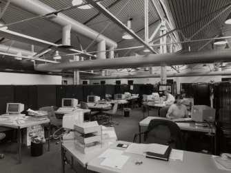 Interior view of office area, within which yellow in/out trays match overhead ducts
