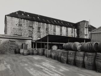View from S of SE wing of works, with whisky barrels in foreground undergoing re-conditioning.  Photosurvey 23-APR-1992