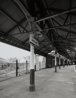 View of cast-iron columns and steel trusses supporting platform canopy, and railings on E side of station.