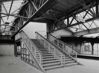 View from NE of staircase leading up from southbound platforms to main station offices at road level on bridge above.