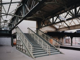 View of staircase leading up from southbound platforms to main station offices at road level on bridge above.