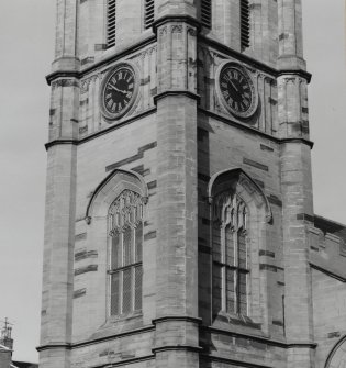 View of second stage of tower showing traceried windows and clock faces.