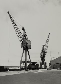 King George V Wharf, view from NE showing Stothert and Pitt electric powered 7 ton travelling keyside cranes built in 1971. Dock crane nos. 49 and 50.
Photographed 28 July 1987