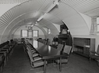 Interior view of officers mess, conference room (hut 27) showing meetings table, seating and fireplace