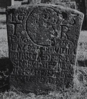 Dunning, St. Serf's Parish Church, Graveyard.
General view of the West face of the tombstone commemorating Thomas Rutherford, 1693. A profile head/skull with inscription.
Insc:'1693 T.R.Thomas Rutherford. Lays. Heir...With...Imprisoned. For...Sin. But...Rest. In. Houp..To. Be. Set. By The Second. Adam..'.
