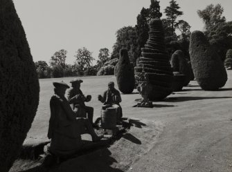 Fingask Castle, statuary.
General view of sculptures in grounds showing three men drinking around a barrel with Holyrood Palace sundial in background.