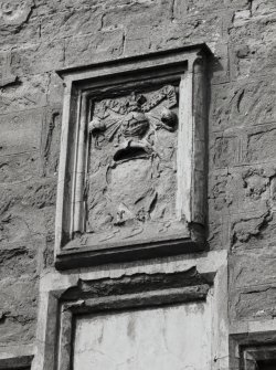 Armorial panel over doorway in exterior gable-end of S burial-aisle.