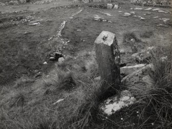 Oblique view of rear of cross-marked stone, number.3, with settlement site in background, on Isle of Pabbay.