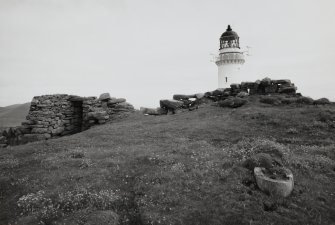 View of surviving West wall and entrance way to Dun Briste site, with Barra Head Lighthouse in background, Isle of Berneray.