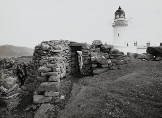 View, from West, of surviving doorway in ruined wall at Dun Briste site and Barra Head Lighthouse in background, Isle of Berneray.