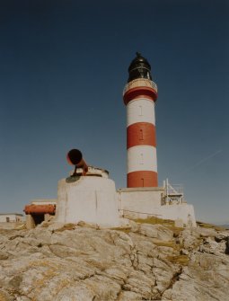 View from S of new lighthouse tower  (built 1826) and fog horn, with rocks in foreground
