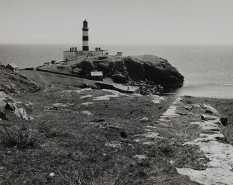 General view from NW of lighthouse complex and associated harbour, with remains of road/path leading through outer compound in foreground