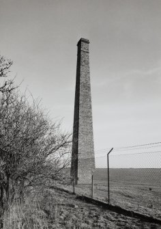 View from NW of tapered, square-section fireclay brick chimney stack, forming part of the remains (otherwise mostly concrete foundations) of the recovery Ether Plant (NY 342 673)