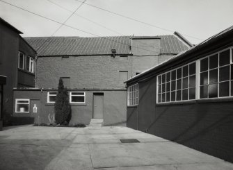 View from S of former floor-maltings block (now a store), with part of office building (left), evaporator house (right)