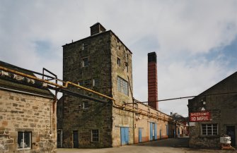 View from SW of W end of boiler-house range, with former still house in foreground, and chimney (centre)