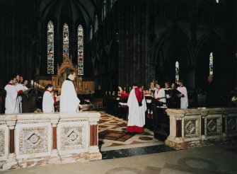 Interior.
View of choir and apse ended chancel with director of music conducting choristers.