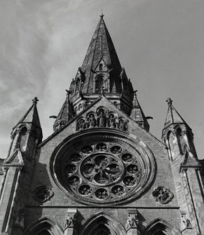 Detail of SE transept's end elevation showing gable with wheel window, niches, quatrefoils and pinnacles, with main tower rising behind.