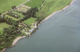 Oblique aerial view centred on the lighthouse and cottages with house and cemetery adjacent, taken from the NNE.