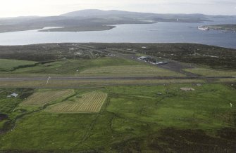 Oblique aerial view centred on the airfield with the oil pipeline terminal in the distance, taken from the SE.