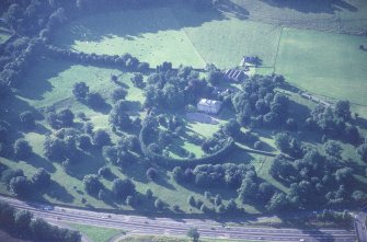 Oblique aerial view centred on the country house with stables and farmsteading adjacent, taken from the SE.