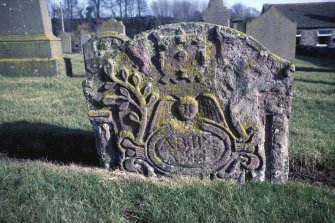 Detail of part buried headstone with winged angel and foliage, Barry Old Parish Churchyard.