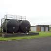 View.  Diesel fuel tanks for emergency generators with workshop/garage in background from E.