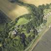 Oblique aerial view centred on the country house, cottage and church, taken from the SW.