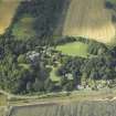 Oblique aerial view centred on the country house, cottage and church, taken from the SSE.