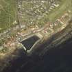 Oblique aerial view of the village centred on the harbour with the cottages and dairy adjacent, taken from the SSE.