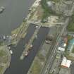 Oblique aerial view centred on the burnt out sugar warehouse and the docks, taken from the WNW.